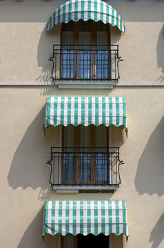 Italian balconies.Facade of an old hotel with striped awnings in Garda, Italy