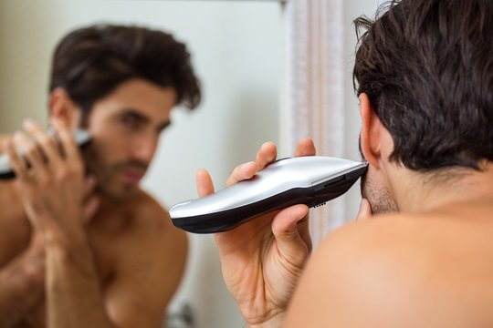 Young man shaving with trimmer