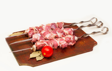 barbecue, raw juicy slices of meat on skewers with sauce on kitchen board