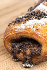 Chocolate croissant on a wooden board isolated on white