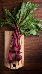 Beet on cutting board overhead and brown wooden table in studio