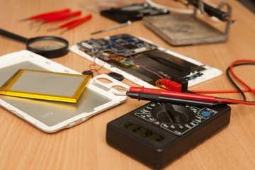 Disassembled tablet and tools on a wooden background. View from