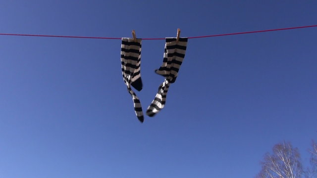 Striped white and black socks drying on a rope outside on sunny spring day