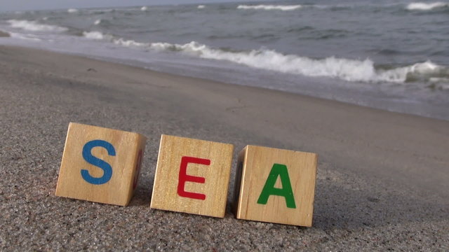 Word &ldquo;sea&rdquo; written with multicolored letter cubes on the beach