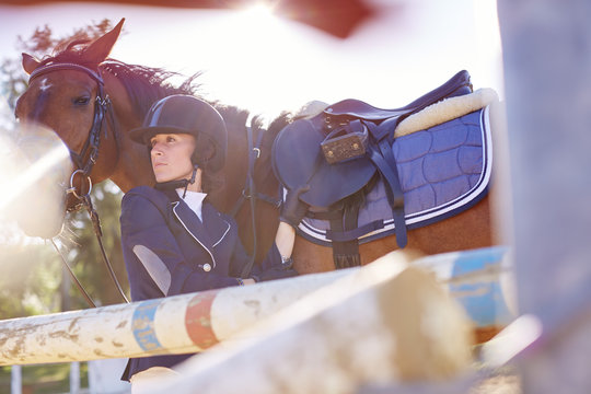 Young woman with horse on show jumping course