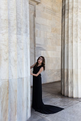 young lady in black dress near column