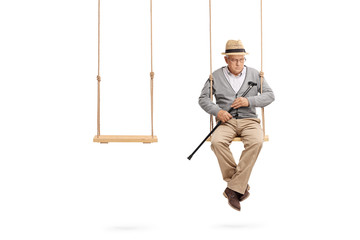 Lonely senior sitting on a wooden swing