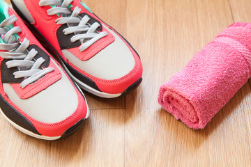 red and grey sneakers with grey shoelaces and red towel on wooden background indoors