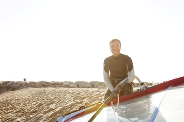 Smiling man on the beach with surfboard