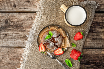 Chocolate fondant  with strawberry , mint  and milk on the wooden table