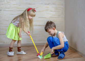 Cute children using toy broom and dustpan