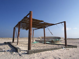 Shelter and fishing boat on a beach, Masirah Island, Oman