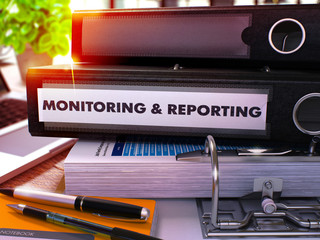 Black Office Folder with Inscription Monitoring and Reporting on Office Desktop with Office Supplies and Modern Laptop. Monitoring and Reporting Business Concept on Blurred Background. 3D Render.