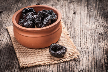 Prunes in bowl on linen and rustic wood