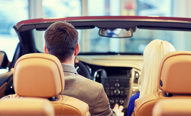 couple sitting in cabriolet car at auto show