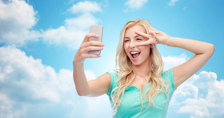 smiling young woman taking selfie with smartphone