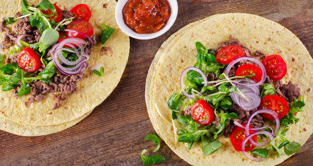 Two mexican tacos on rustic wooden background.