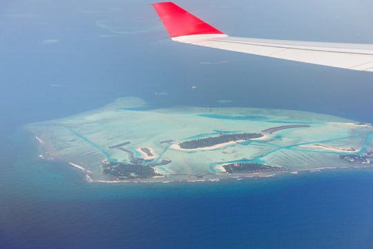 close up of airplane wing above island in ocean