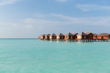 bungalow huts in sea water on exotic resort beach
