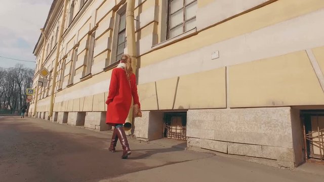 Young blond woman walking in European city on Sunny spring day