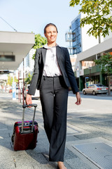 Business woman pulling suitcase bag walking in city