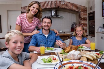 Portrait of happy family having meal in kitchen
