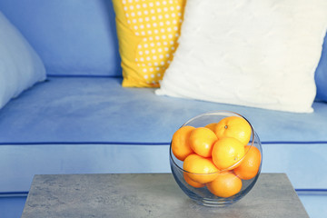 Bowl with fresh tangerines on table in living room, close up