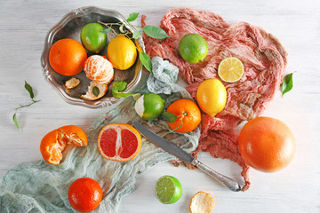 Fresh citrus fruits with green leaves on wooden table closeup