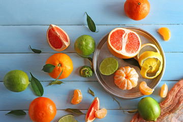 Fresh citrus fruits with green leaves on wooden table closeup