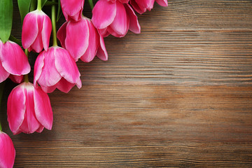 Fresh pink tulips on a wooden table, top view