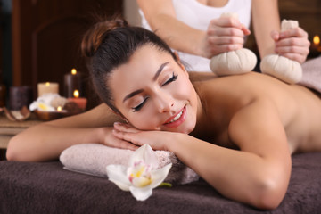 Fototapeta na wymiar Beautiful young girl having massage with herbal balls in spa salon