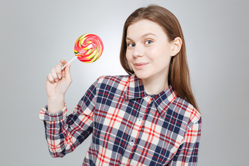 Smiling beautiful teenage girl in checkered shirt holding lollipop