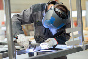 Man leaning over welding - obrazy, fototapety, plakaty