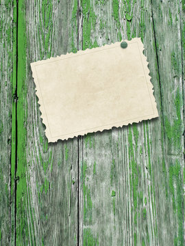 Close-up of one blank brown old vintage postcard frame with pin on grey and green weathered wood background