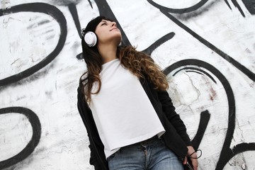 Girl listening to Music while leaning on a Wall.