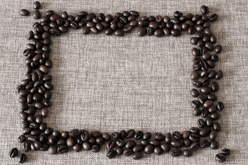 Frame made of coffee beans on sack cloth background.