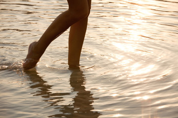 jambes de femme qui marchent dans le sable à la plage le soir