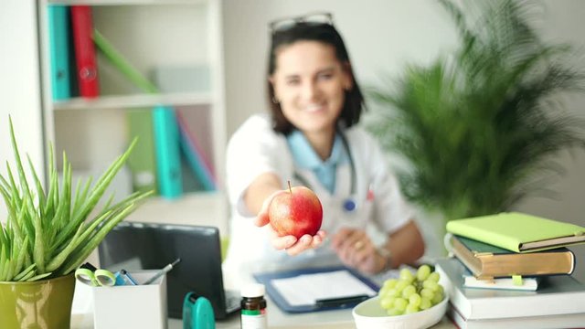 Doctor giving apple to the patient while sitting in the office
