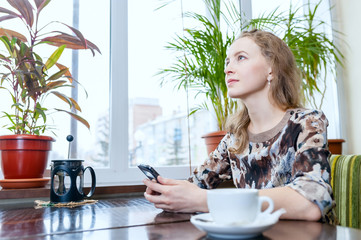 young beautiful girl in a cafe with a smartphone in the hands of