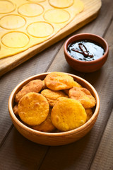 Traditional Chilean Sopaipilla fried pastry made with mashed pumpkin in the dough, served with Chancaca sweet sauce, photographed on wood with natural light (Selective Focus)