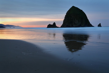 Cannon Beach, Haystack Rock Dawn, Oregon, USA. Sunrise at Haystack Rock in Cannon Beach, Oregon as the surf washes up onto the beach. United States.
