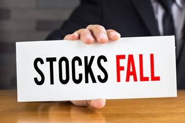 Stocks fall, message on white card and hold by businessman