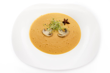 Cream of mushroom soup in a white plate on a white background.