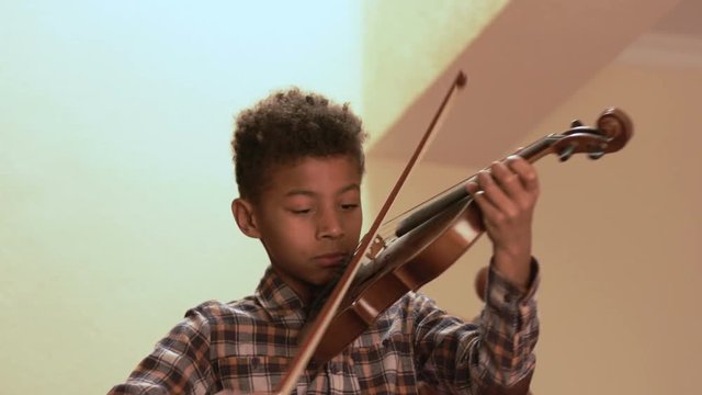 Smiling afro kid plays on violin.