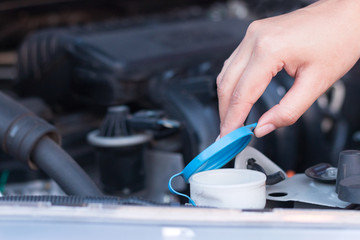 Closeup woman's hand opening windscreen water tank.