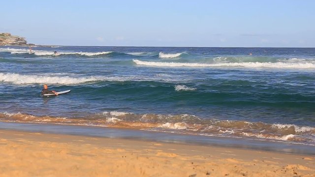 Big beautiful turquoise waves breaking on a sandy beach and surfer with a board enters the ocean at a beach in Australia a good clear weather