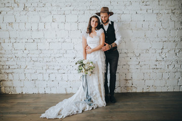 girl with a wreath of white flowers on the head in a white wedding dress and a bearded man in a...