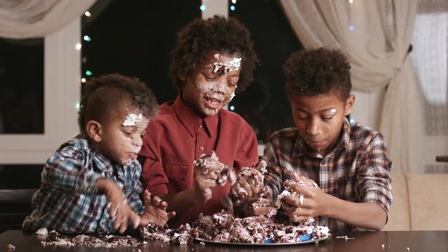 Afro kids greedily eating cake.
