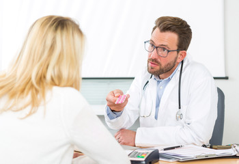 Young attractive doctor giving pills to a patient