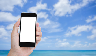 Hand holding blank screen mobile phone with seascape and  clouds